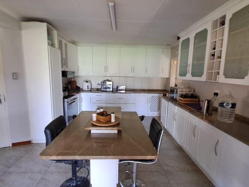 Spacious kitchen featuring white built-in cabinetry, granite countertops, and a central breakfast island, providing ample storage and workspace for meal preparation.