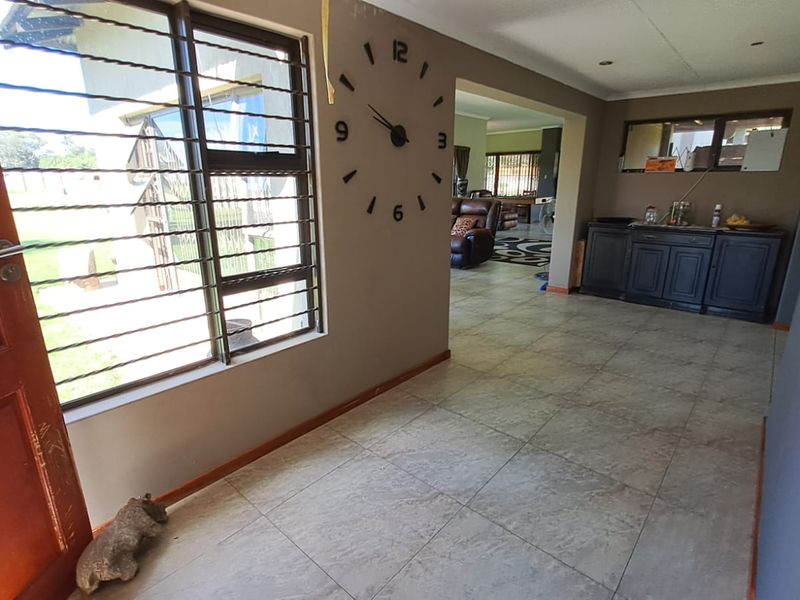 Entrance hall featuring tiled flooring, security bars on windows, and built-in cabinetry, leading into an open-plan living area.