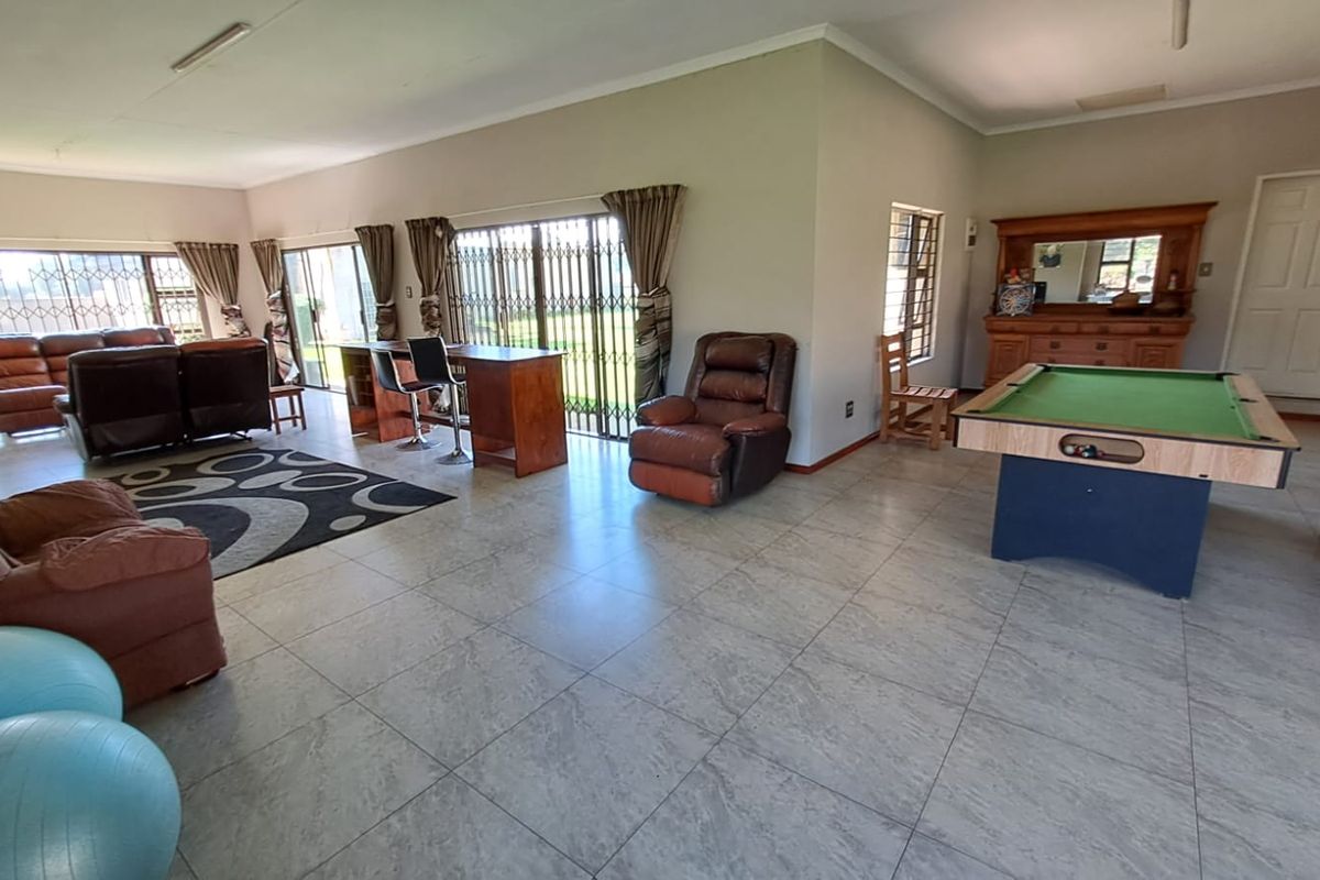 Spacious open-plan living area featuring large format floor tiles, security gates on sliding doors, and neutral wall finishes.