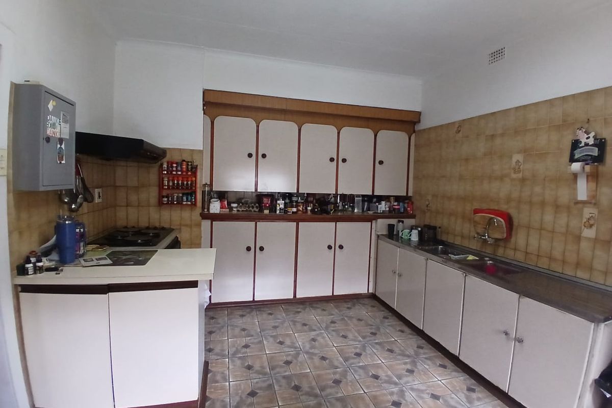 A functional kitchen featuring dated cabinetry, tiled splashbacks, and a gas hob, offering significant potential for a modern renovation.