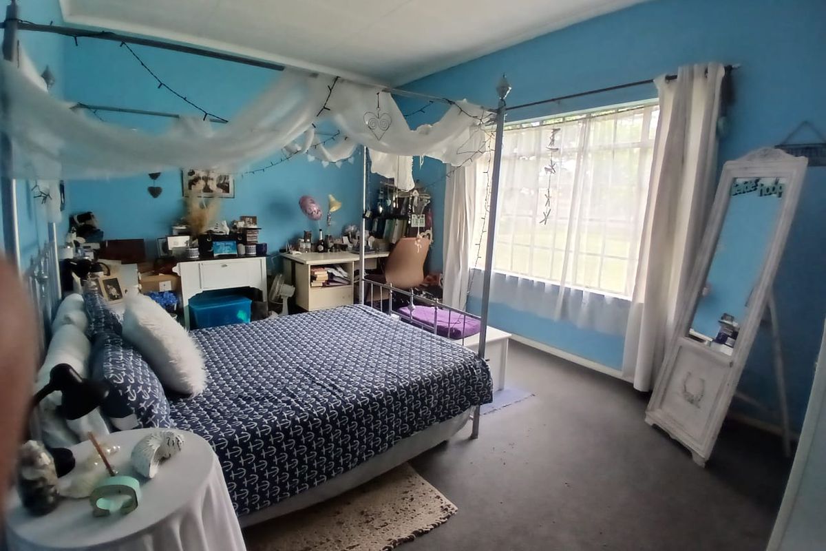 A spacious bedroom featuring a large window that allows for natural light, finished with carpeted flooring.