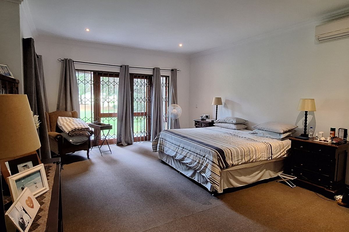 Spacious bedroom featuring carpet flooring, air conditioning, and direct access to the garden through sliding glass doors with security gates.