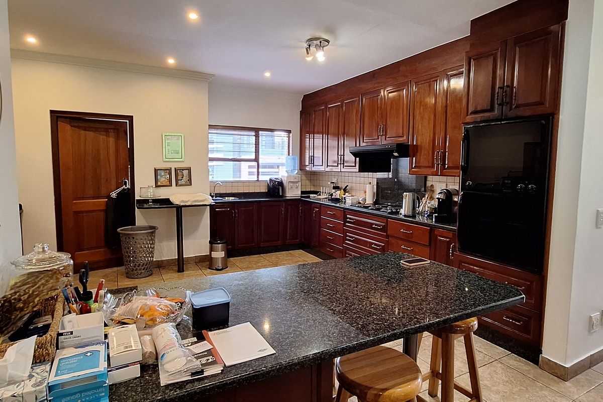 A functional kitchen featuring dark wood cabinetry, granite countertops, built-in oven, and a central island, offering ample storage and workspace.