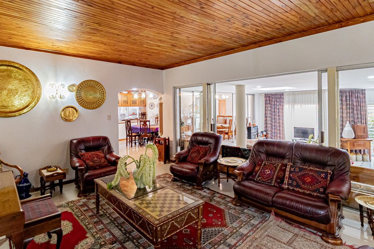 Spacious living room featuring a warm timber tongue and groove ceiling, large sliding glass doors, and an open-plan flow to the dining and kitchen areas.