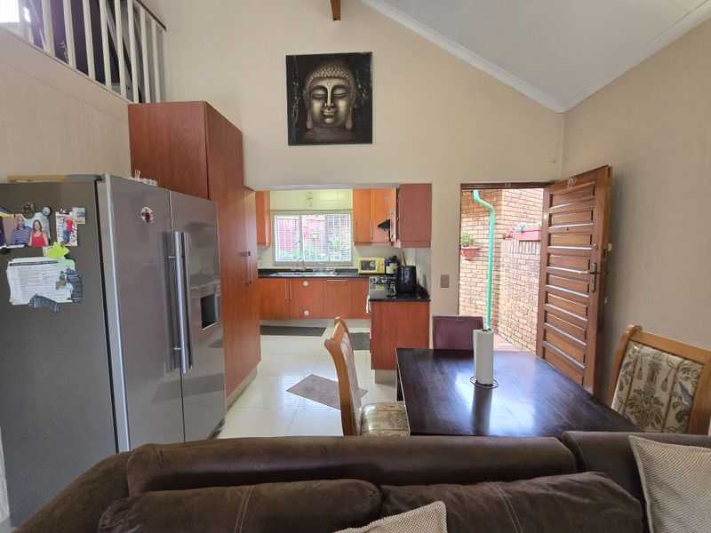 Open-plan living and dining area featuring a functional kitchen with wood-finish cabinetry, tiled flooring, and direct access to an outdoor courtyard space.