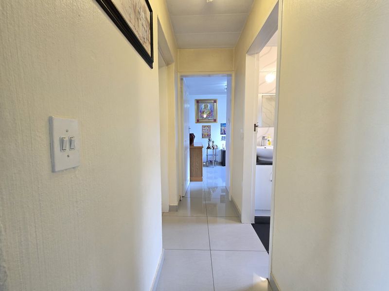 A bright interior hallway featuring tiled flooring, connecting multiple rooms within the property.
