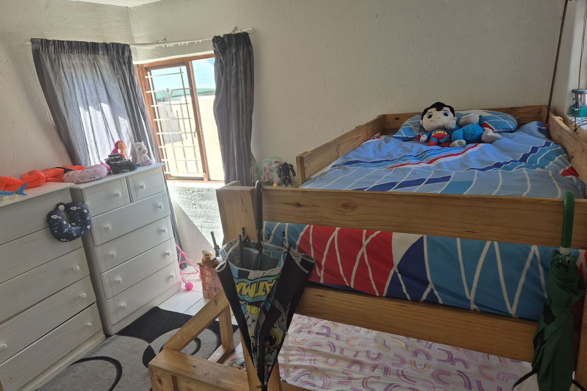 A bedroom featuring a bunk bed, tiled flooring, and security bars on the window.