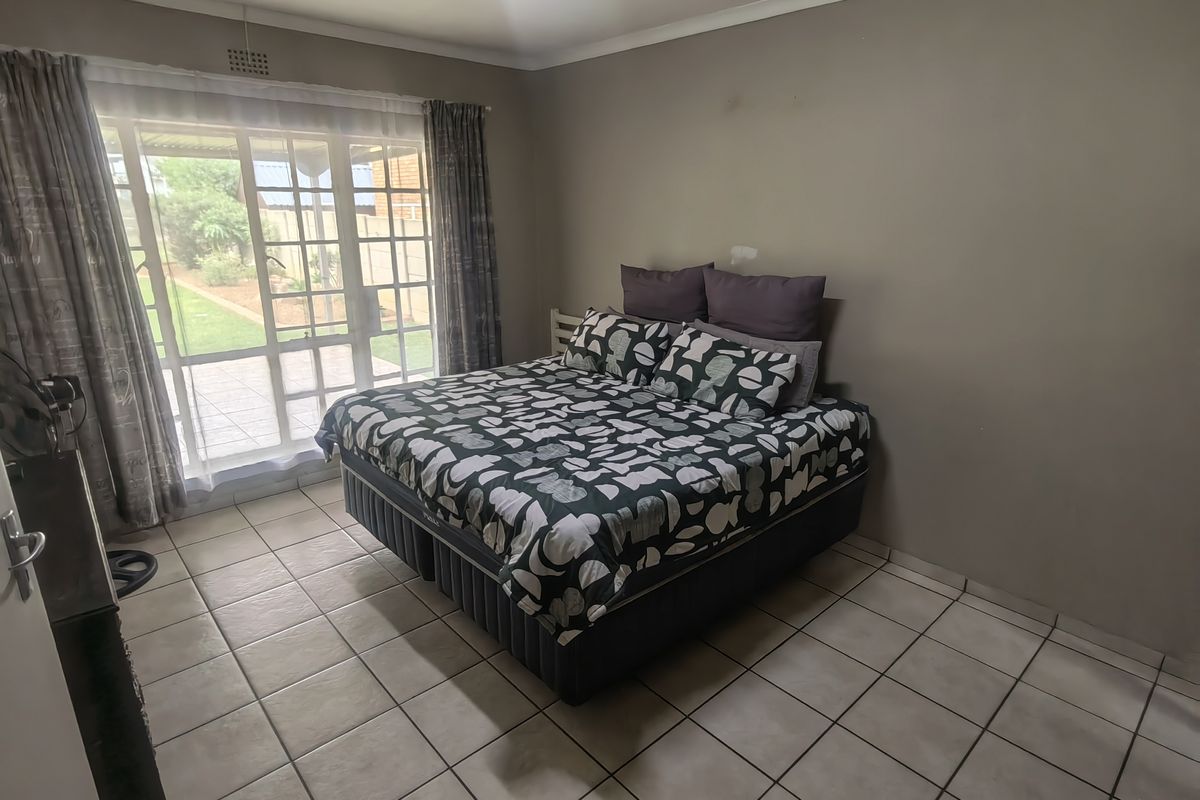 A bedroom featuring tiled flooring and a large sliding glass door providing natural light and access to the outdoor area.