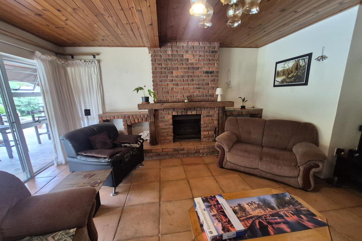 Living room featuring a prominent brick fireplace, timber-clad ceiling, and terracotta floor tiles with direct access to an outdoor patio area.