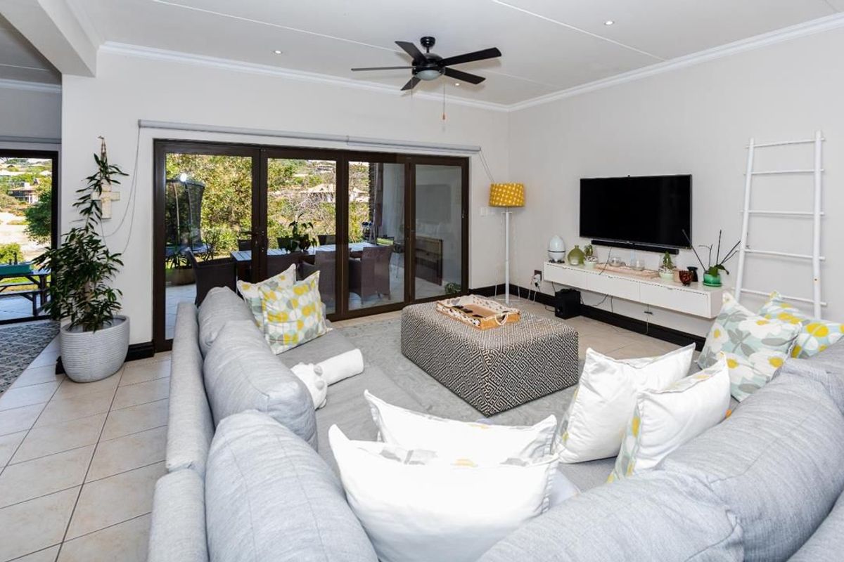 Spacious living room featuring tiled flooring, a ceiling fan, and large sliding glass doors that provide seamless access to the outdoor patio area.