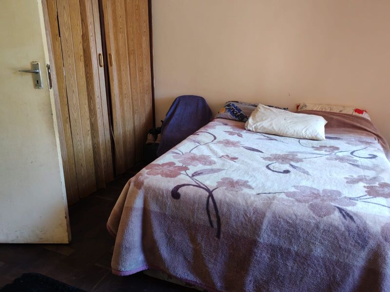 A bedroom featuring built-in wooden wardrobes and parquet flooring, requiring cosmetic updates to improve the overall aesthetic and condition.