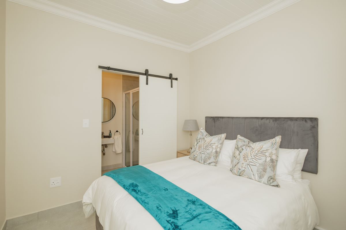A well-maintained bedroom featuring crown molding, tiled flooring, and a sliding barn door providing access to an en-suite bathroom.