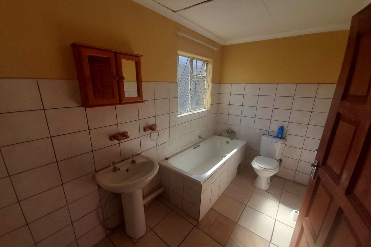 A dated bathroom featuring a pedestal basin, a built-in bathtub with tiled surround, and a standard toilet, finished with ceramic wall and floor tiles.