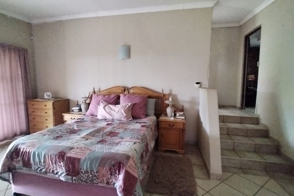 A bedroom featuring tiled flooring, a split-level layout with stairs leading to an adjacent area, and neutral wall finishes.