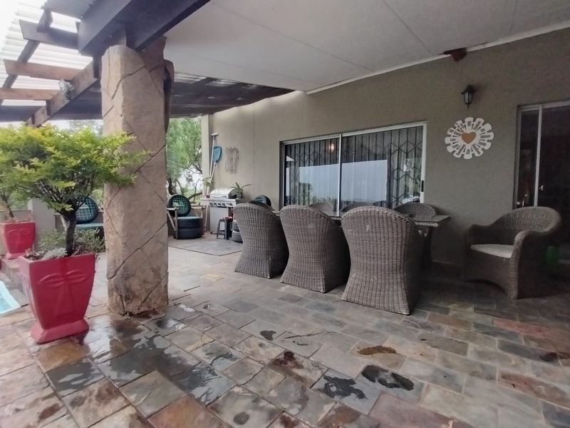 Covered outdoor patio area featuring natural stone paving, a textured support pillar, and direct access to the home through sliding glass doors.