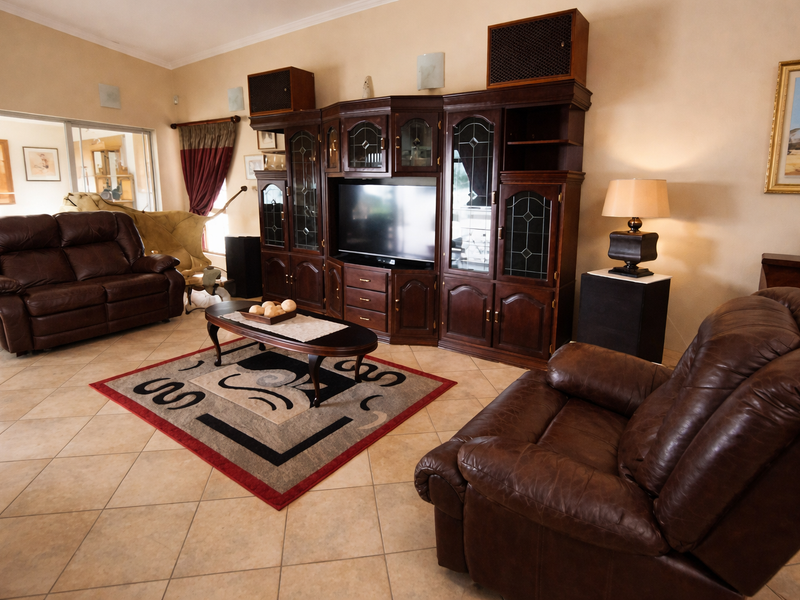 Spacious living room featuring tiled flooring, high ceilings, and a large built-in wooden entertainment unit.