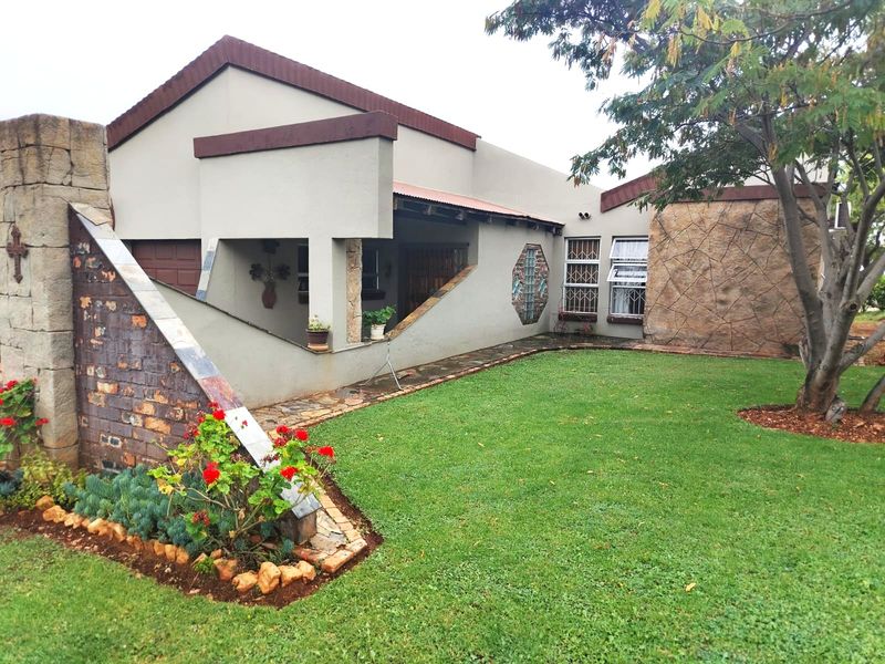 Front exterior view of the house featuring a landscaped garden, stone-clad feature wall, and a covered entrance area with unique architectural detailing.