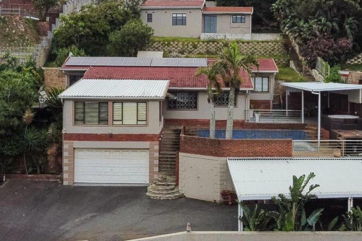 Aerial view of a multi-level residential property featuring a swimming pool, solar panels, double garage, and extensive paved outdoor areas.