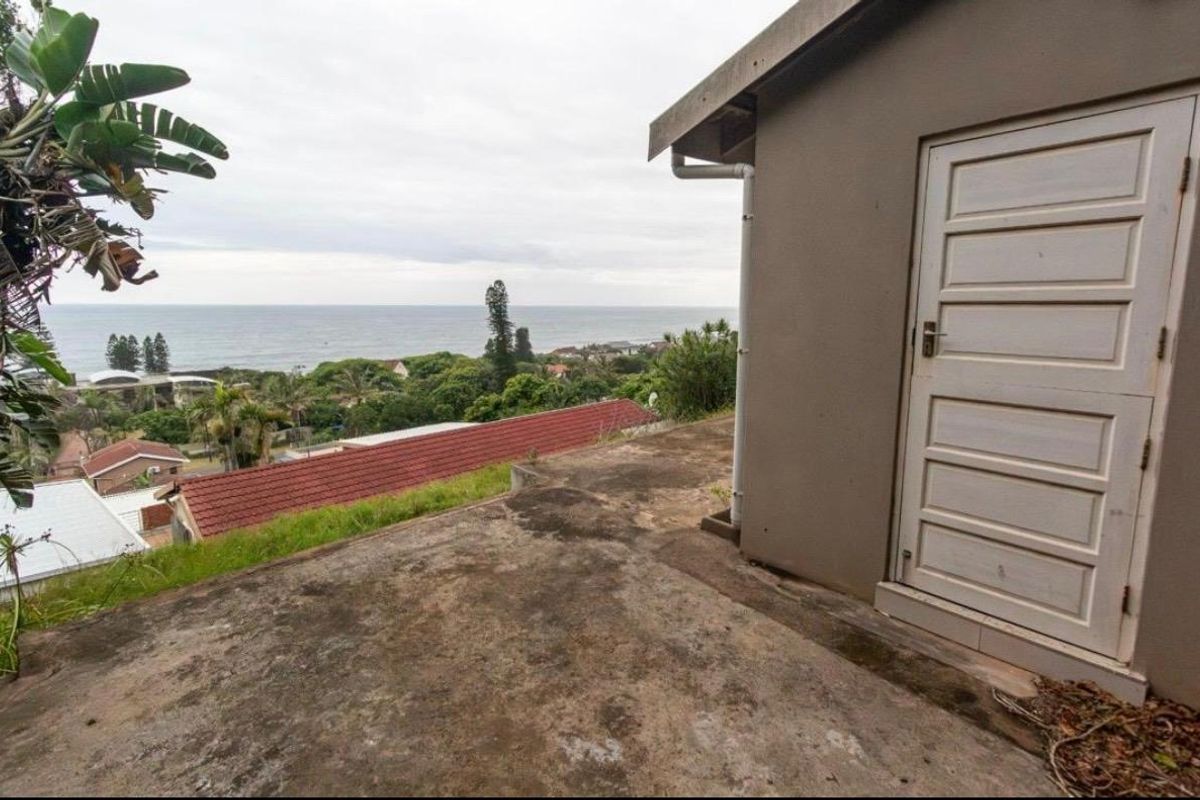 An exterior rear view featuring a concrete patio area with a coastal outlook and a side entrance door.