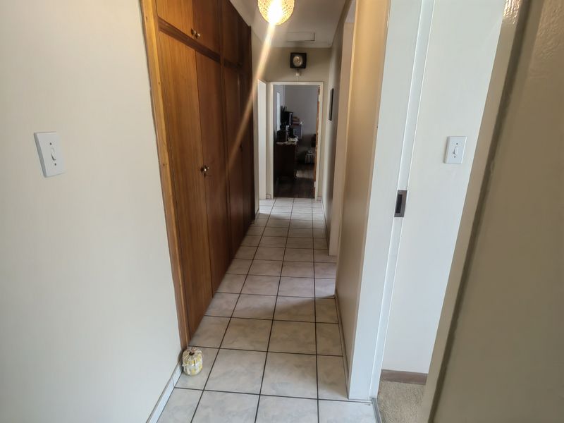 A functional hallway featuring tiled flooring and extensive built-in wooden cabinetry for storage, connecting various areas of the home.