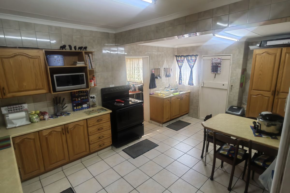 A functional kitchen featuring wooden cabinetry, tiled backsplash, tiled flooring, and a freestanding stove, offering a traditional layout with ample storage space.