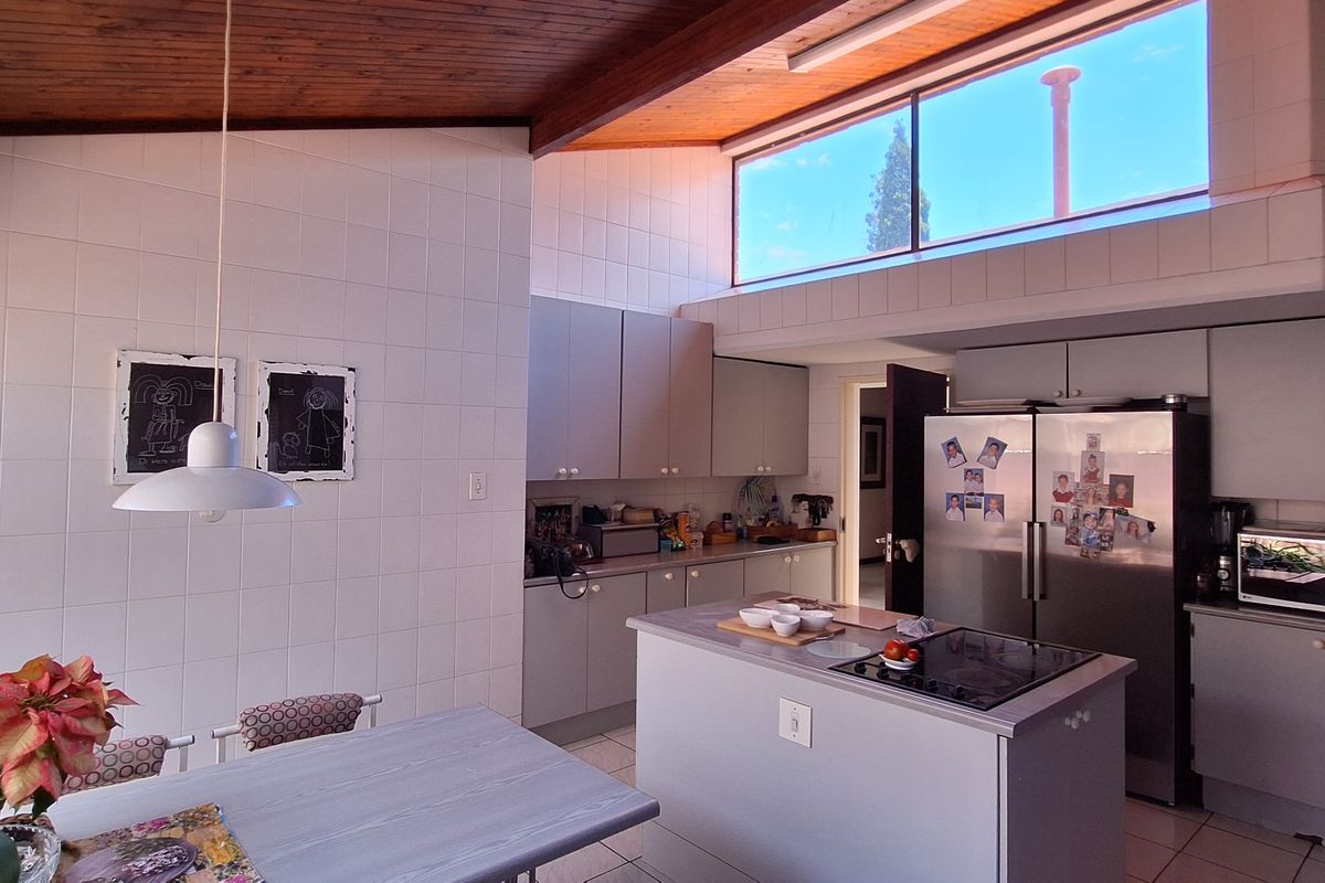 Spacious kitchen featuring a central island with integrated cooktop, ample cabinetry, and high timber-paneled ceilings with clerestory windows providing natural light.