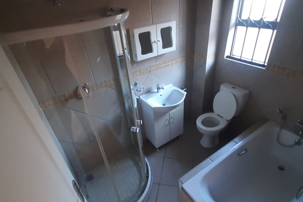 A functional bathroom featuring a separate shower enclosure, bathtub, vanity basin, and toilet with tiled finishes throughout.