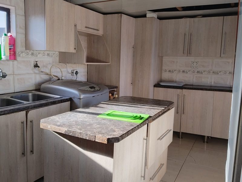 Kitchen featuring light wood-look cabinetry, laminate countertops, and a central island. The space requires ceiling completion and minor repairs to finishes.