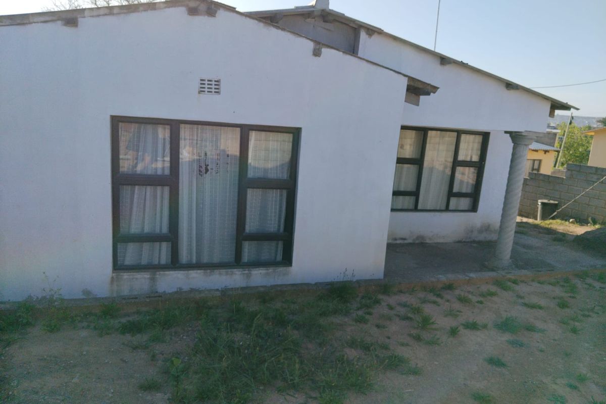 Rear view of the house featuring a covered patio area with a concrete column and aluminium window frames.