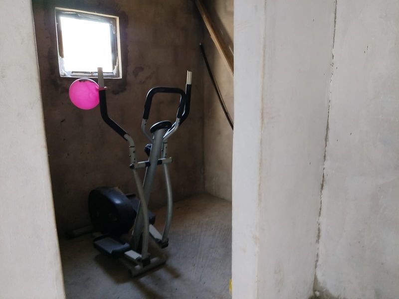 A small, unfinished utility space featuring raw concrete walls and a small window, currently used for storage.