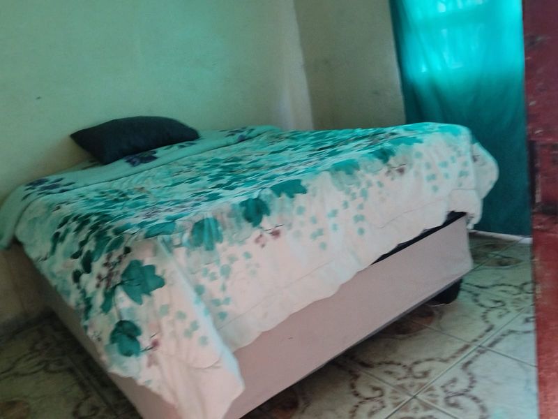 A bedroom featuring tiled flooring and painted walls, currently requiring cosmetic updates to improve the overall condition and aesthetic appeal.