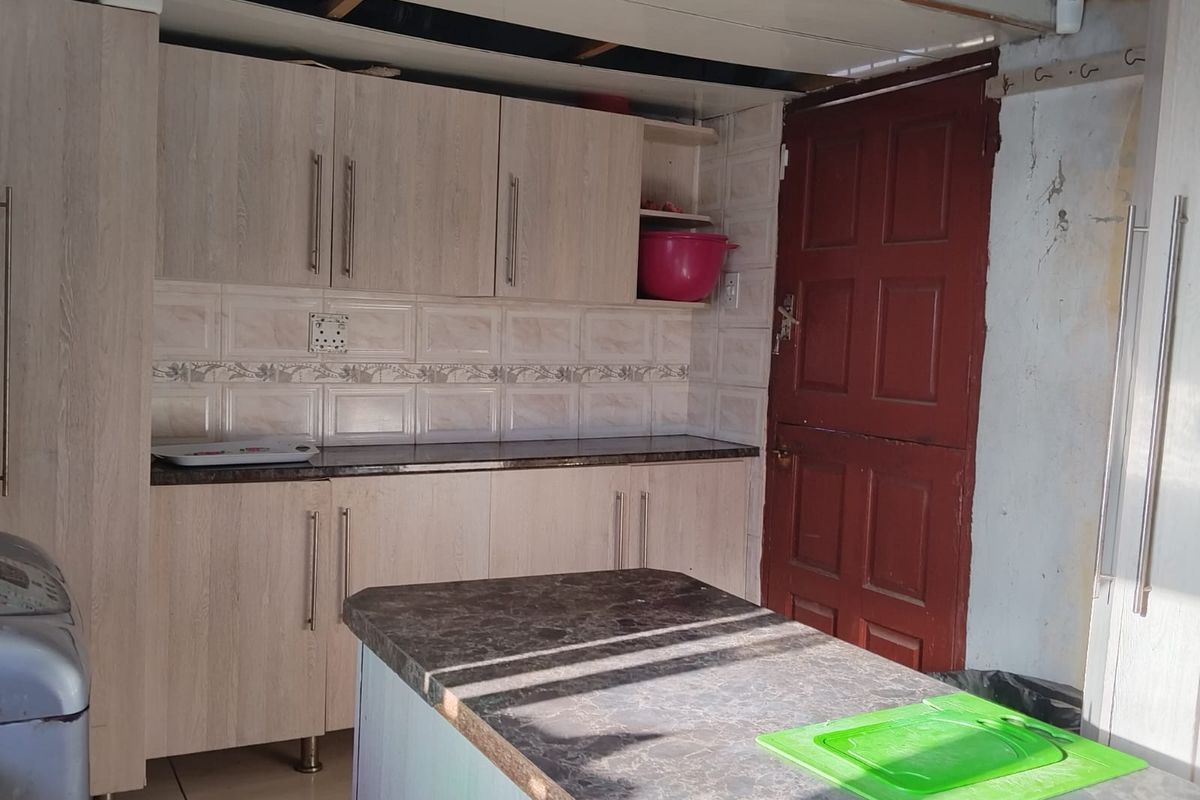 A kitchen area featuring light wood-finish cabinetry, tiled backsplash, and a central island, currently requiring ceiling and wall repairs.