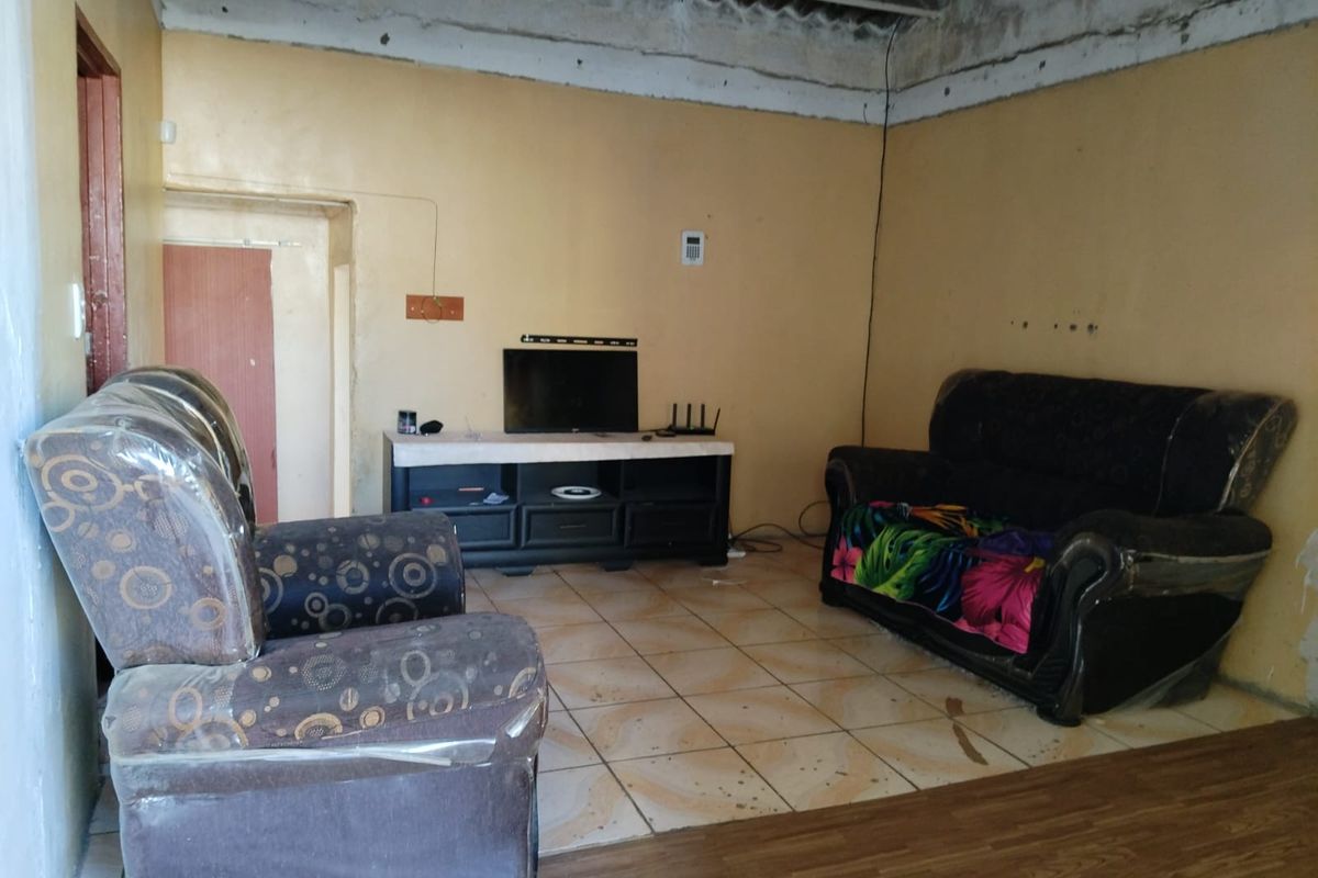A living room area featuring ceramic floor tiles and an unfinished ceiling, requiring cosmetic updates and repairs to improve the overall condition.