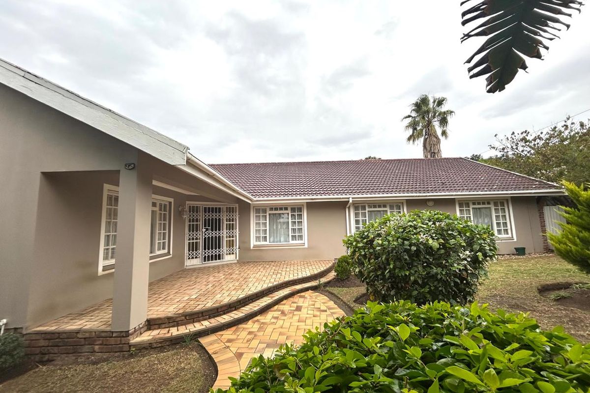 A well-maintained rear exterior view featuring a paved patio area, tiled roof, and secure entrance access to the home.