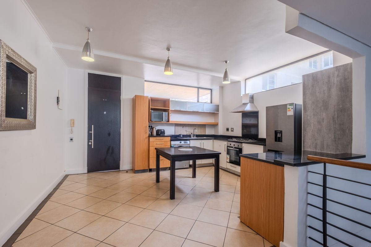 A functional kitchen featuring wood-finish cabinetry, granite countertops, built-in oven with gas hob, and tiled flooring, offering a practical layout for daily use.