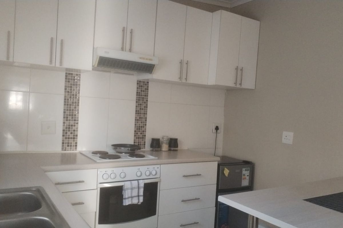A functional kitchen featuring white cabinetry, laminate countertops, a tiled backsplash, and integrated cooking appliances including an oven and hob.