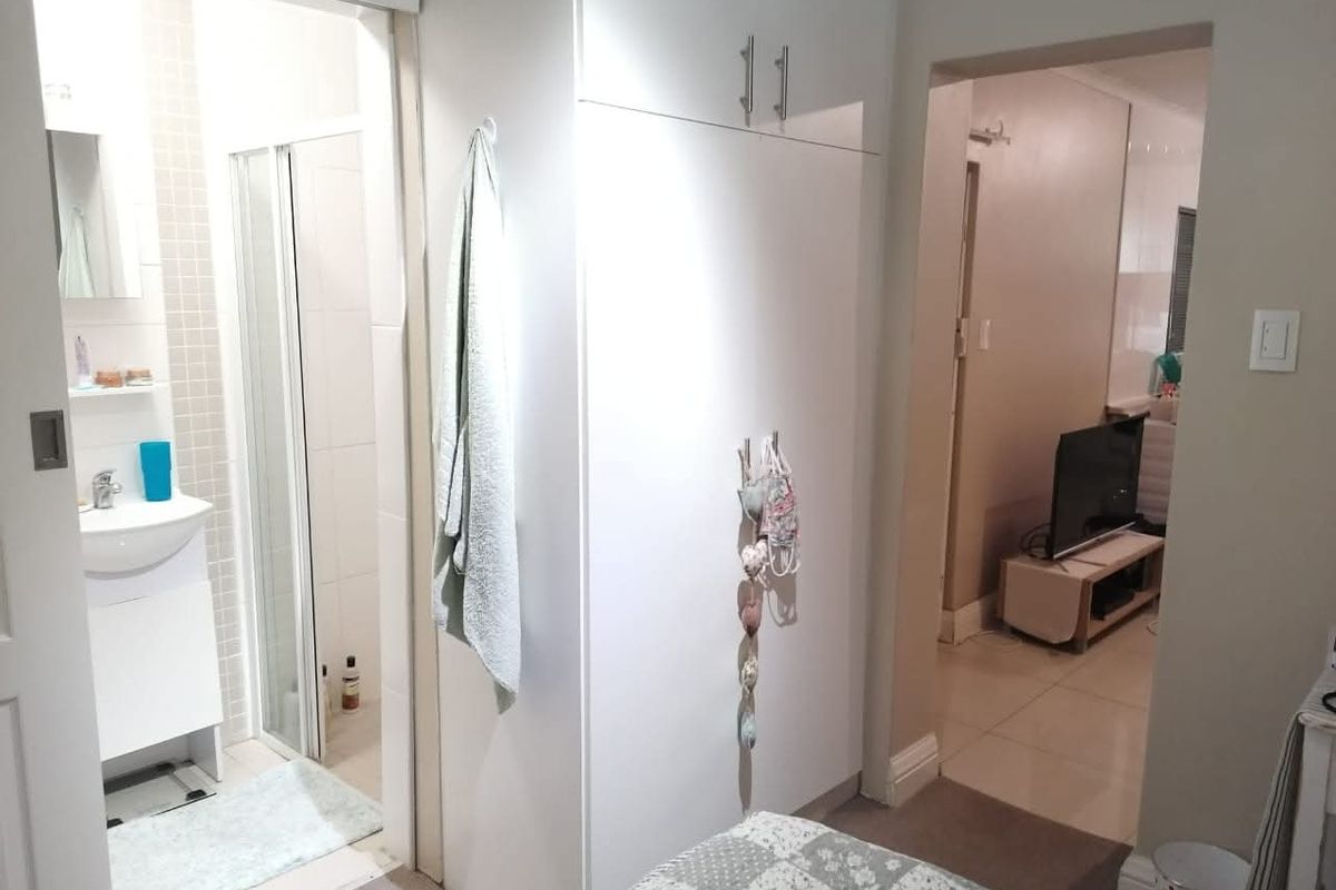 Bedroom featuring built-in wardrobe storage and direct access to an en-suite bathroom with a shower and vanity.
