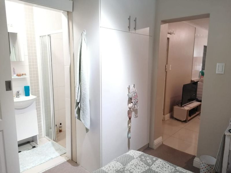 Bedroom featuring built-in wardrobe storage and direct access to an en-suite bathroom with a shower and vanity.