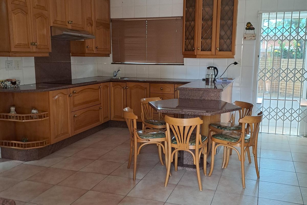 A functional kitchen featuring wooden cabinetry, granite countertops, tiled flooring, and a breakfast nook area with direct access to the exterior.