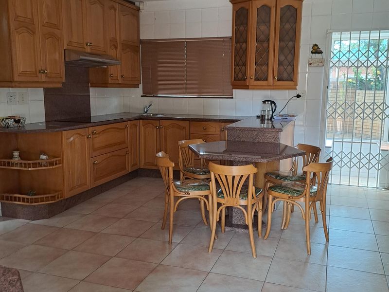 A functional kitchen featuring wooden cabinetry, granite countertops, tiled flooring, and a breakfast nook area with direct access to the exterior.