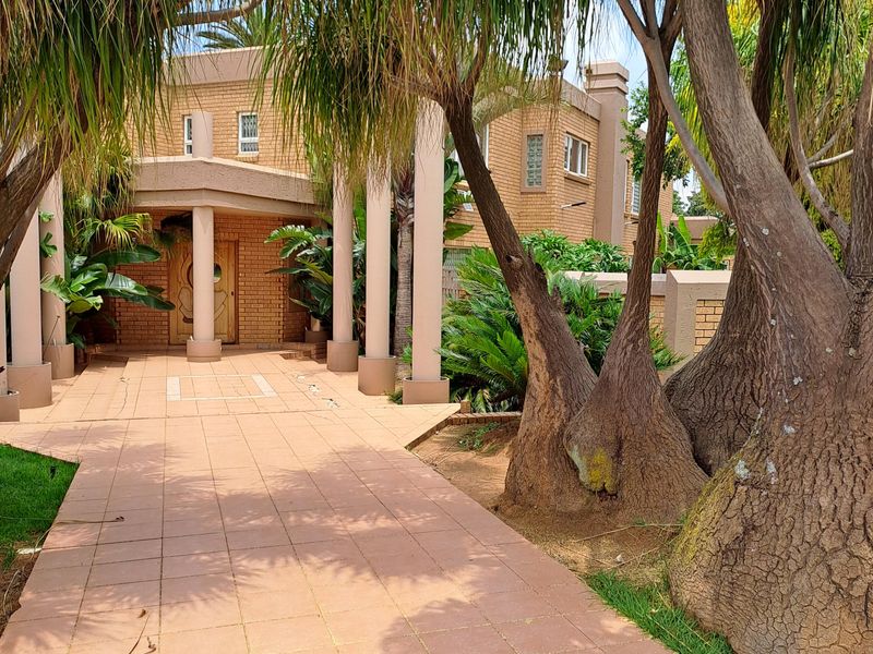 A front entrance view of a brick house featuring a tiled walkway leading to a covered porch supported by structural columns.