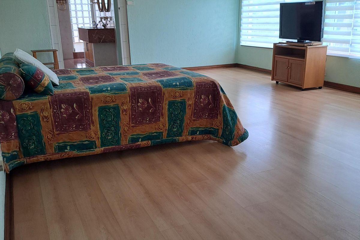 Spacious bedroom featuring laminate flooring, recessed lighting, and venetian blinds, with direct access to an adjoining en-suite bathroom.