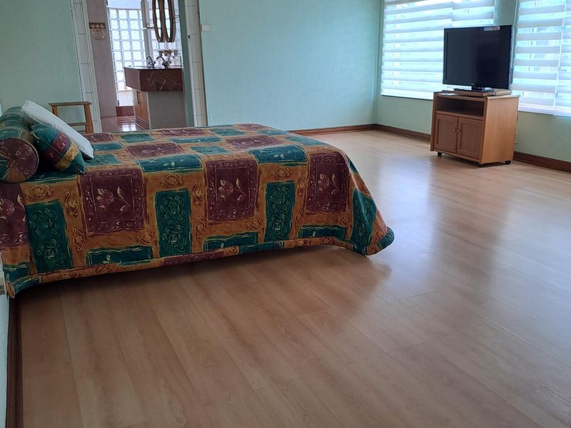 Spacious bedroom featuring laminate flooring, recessed lighting, and venetian blinds, with direct access to an adjoining en-suite bathroom.
