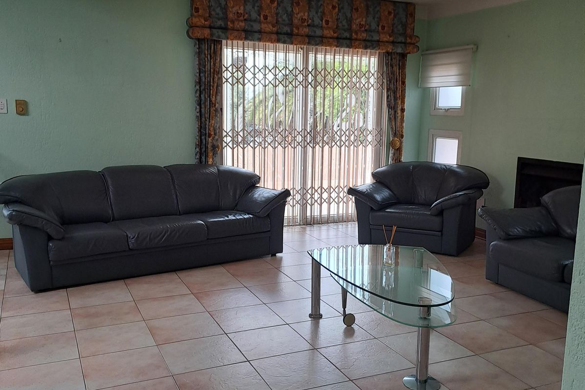 Spacious living room featuring tiled flooring, a built-in fireplace, and sliding glass doors with security gates leading to the exterior.