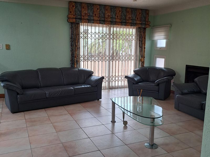 Spacious living room featuring tiled flooring, a built-in fireplace, and sliding glass doors with security gates leading to the exterior.