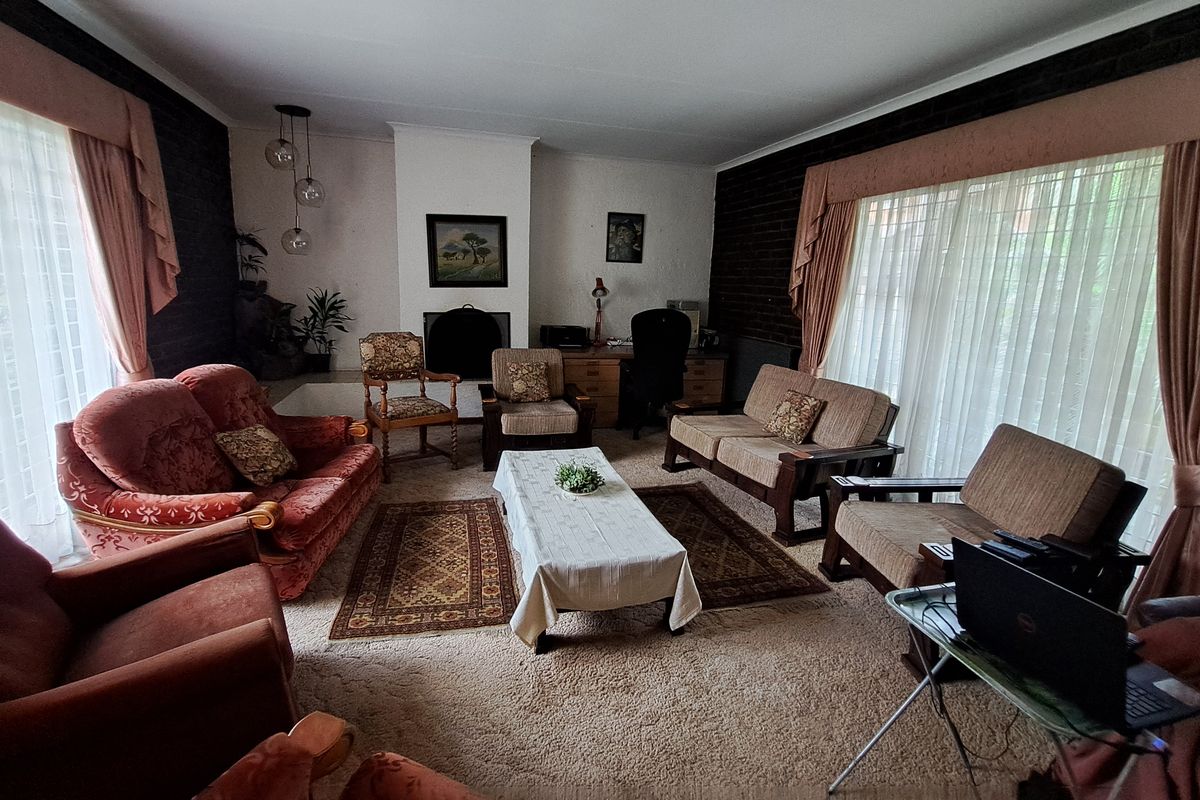 Spacious living room featuring a central fireplace, dark brick accent walls, and large windows allowing for ample natural light.