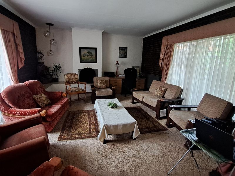 Spacious living room featuring a central fireplace, dark brick accent walls, and large windows allowing for ample natural light.