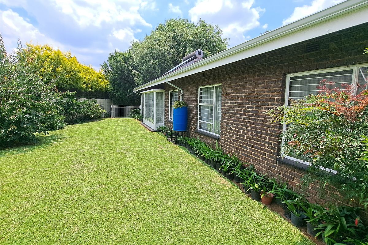 A well-maintained rear garden featuring a brick exterior wall, solar water heating system, and established landscaping.