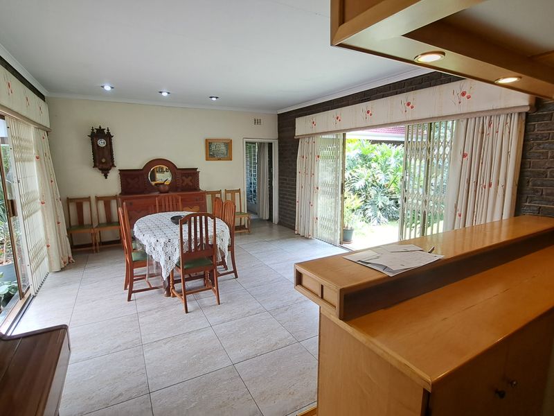 Spacious open-plan dining area featuring tiled floors, exposed brick accents, and large sliding doors providing direct access to the garden.