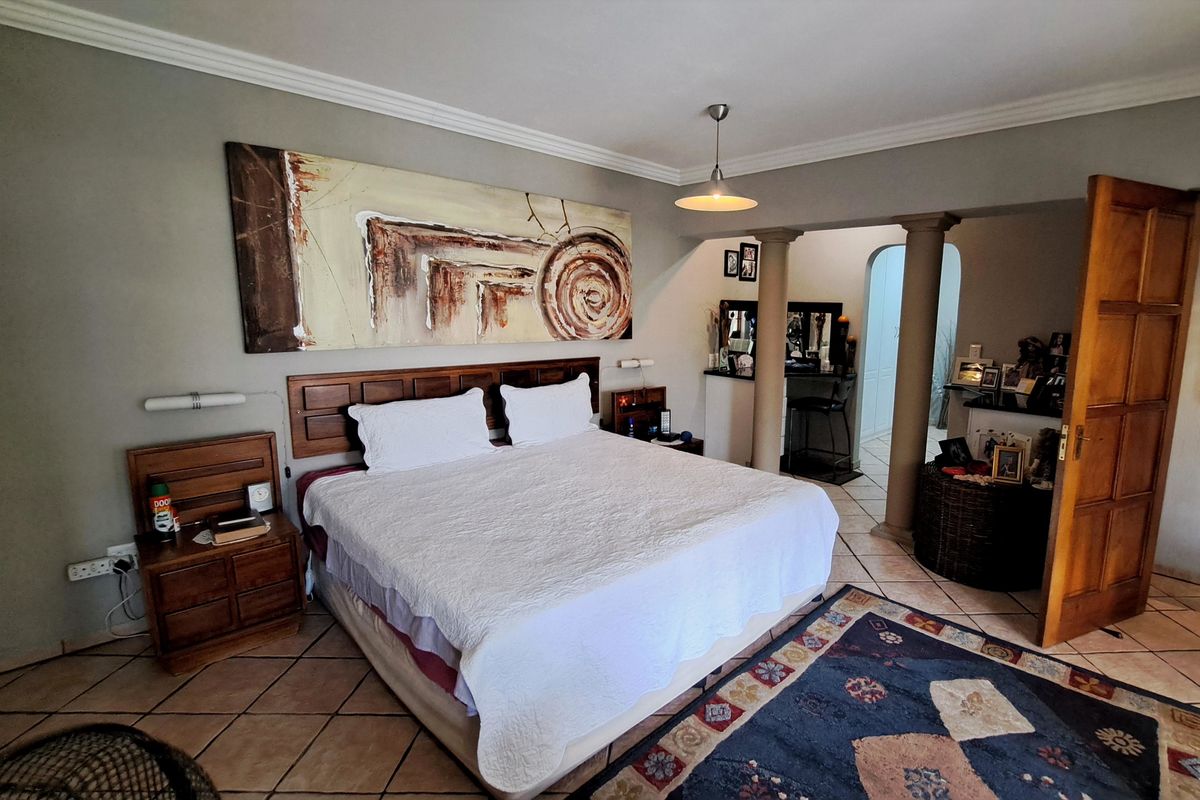 Spacious bedroom featuring ceramic tile flooring, crown molding, and a unique open-plan layout with structural columns leading to an adjacent dressing or vanity area.
